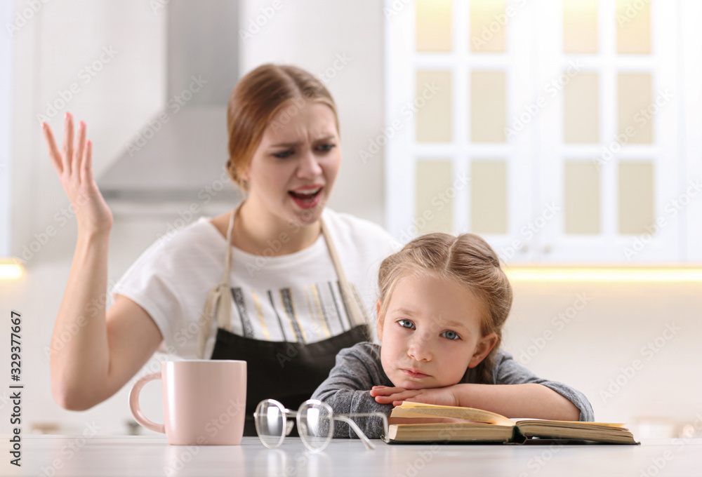 Mother scolding her daughter while helping with homework in kitchen Mother scolding her daughter while helping with homework in kitchen