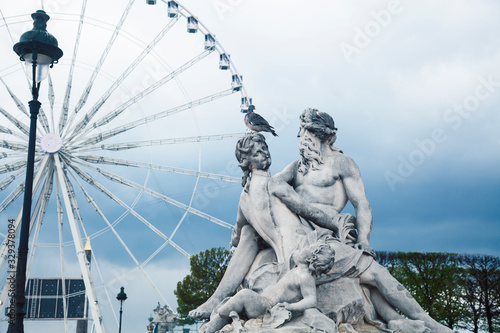 Paris touristic square with garden, sculpture and big ferris wheel on cloudy sky