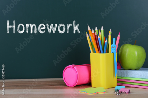 Composition with stationery and apple on table near chalkboard. Doing homework photo