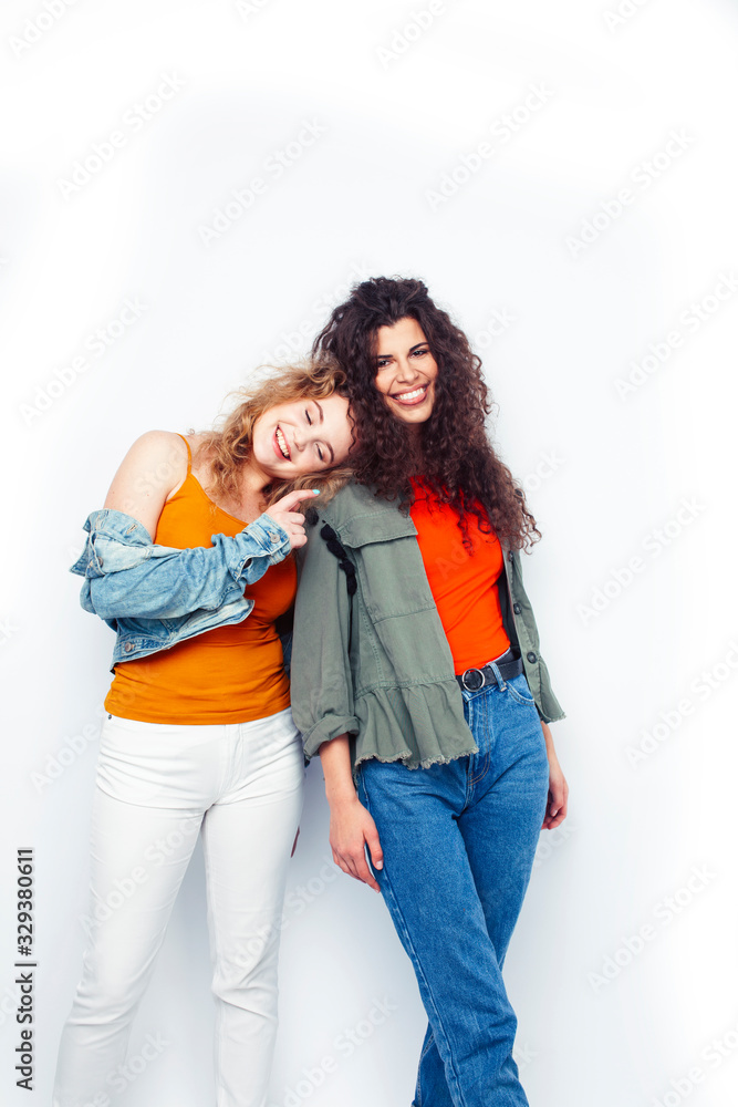 young pretty teenage girls friends with blond and brunette curly hairs posing cheerful isolated on white background, lifestyle people concept young pretty teenage girls friends with blond and brunette curly hairs posing cheerful isolated on white background, lifestyle people concept