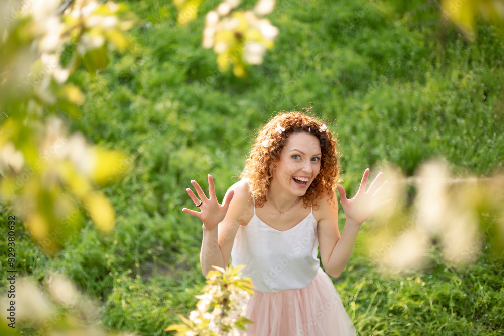 Young attractive girl walks in spring green park enjoying flowering nature. Healthy smiling girl spinning on the spring lawn. Allergy without Young attractive girl walks in spring green park enjoying flowering nature. Healthy smiling girl spinning on the spring lawn. Allergy without