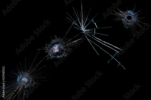 cracks on a black background on broken glass from bullet shots photo