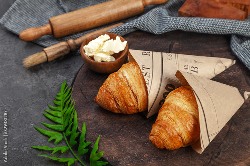 Fresh crispy baked croissants and butter on wooden board