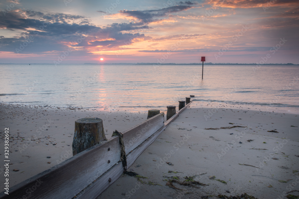 a pink sunrise on a sandy beach with calm water