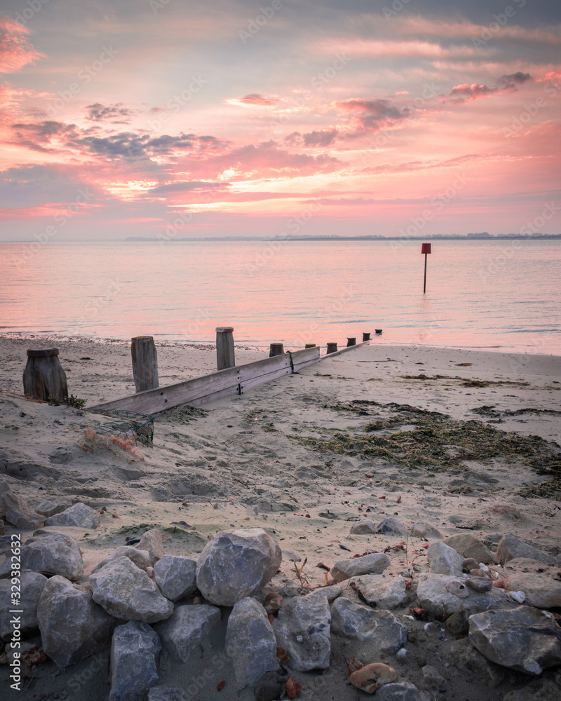 a pink sunrise on a sandy beach with calm water