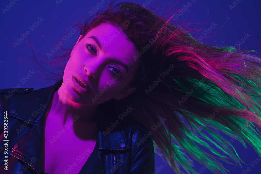 Dancing, hairs flying. Caucasian woman's portrait isolated on blue studio background in neon light. Beautiful female model. Concept of human emotions, facial expression, sales, ad. Trendy colors.