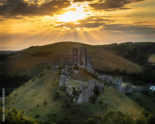 sunrise over corfe castle in dorset with light beams photo