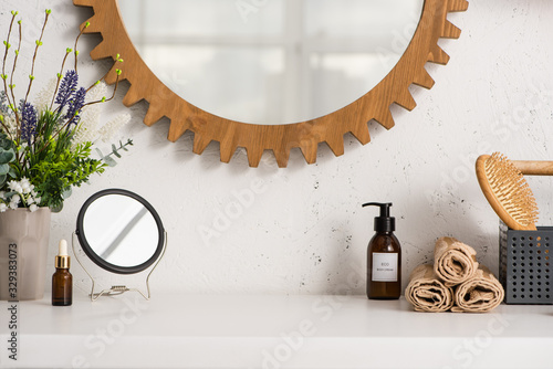 Box with hairbrush, towels near cosmetic products and flowerpot in bathroom, zero waste concept