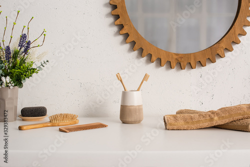 Flowerpot, towels and eco friendly hygiene objects near mirror on wall in bathroom, zero waste concept