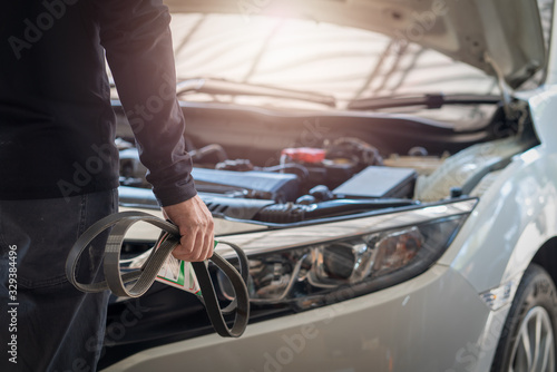 Professional mechanic man holding timing belt of a car for repair and preventive maintenance car in garage
