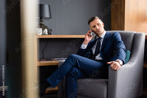 selective focus of businessman in suit talking on smartphone