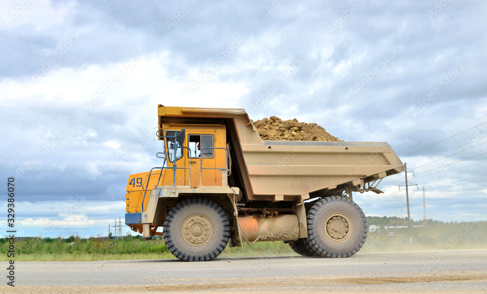 Big yellow mining truck working in the limestone open-pit. Loading and transportation of minerals in the dolomite mining quarry. Belarus, Vitebsk, in the largest dolomite deposit, quarry Big yellow mining truck working in the limestone open-pit. Loading and transportation of minerals in the dolomite mining quarry. Belarus, Vitebsk, in the largest dolomite deposit, quarry