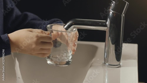 Close-up image of hands trying to fill water from tap to glass. water does not flow after a little flow. 2. photo