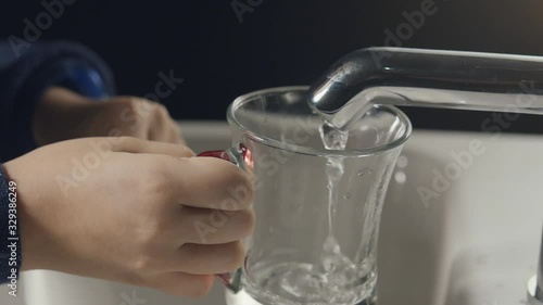 Close-up image of hands trying to fill water from tap to glass. water does not flow after a little flow. 1. photo