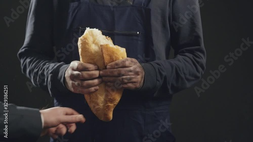 Slow motion image of male hands tearing apart the bread from the laborer. stealing the labor of the worker. photo