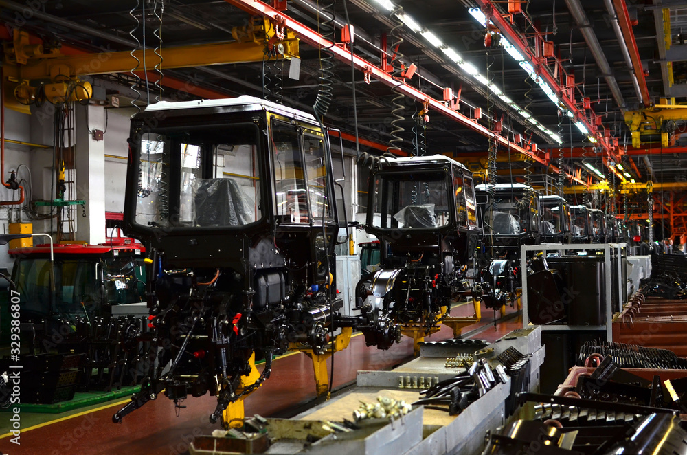Tractor Manufacture works. Assembly line inside the agricultural machinery factory. Installation of parts on the tractor body. Tractor Manufacturing Facility. Tractors produced