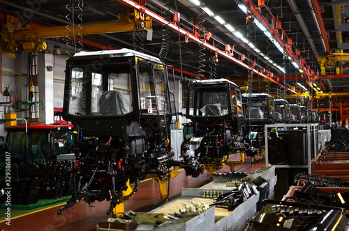 Tractor Manufacture works. Assembly line inside the agricultural machinery factory. Installation of parts on the tractor body. Tractor Manufacturing Facility. Tractors produced