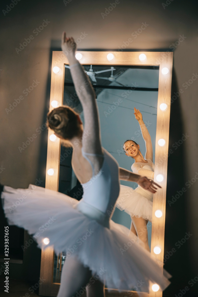 Fototapeta premium Elegant ballerina in white dress dancing in studio