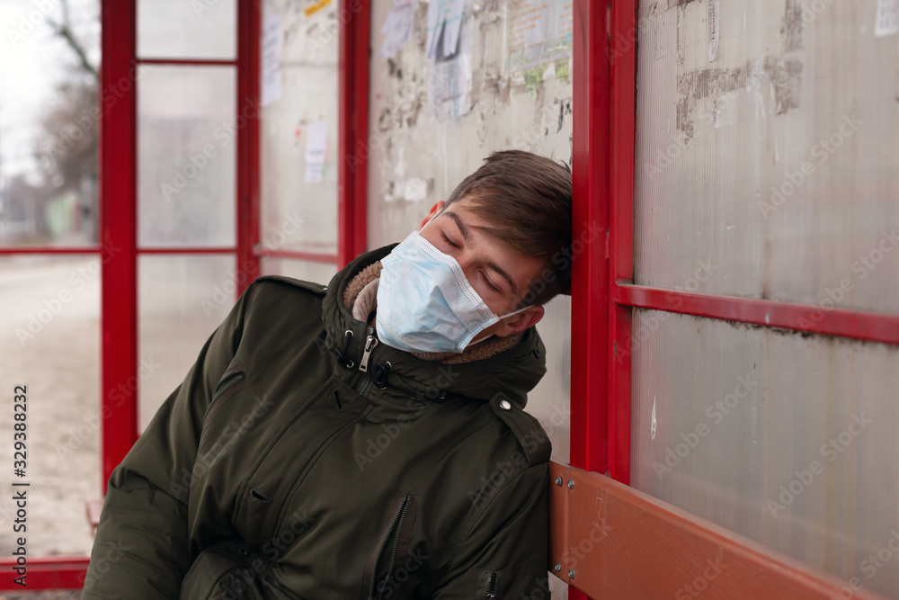 guy sleeps at the bus stop in medical mask close-up respiratory viral disease protection flu covid-19 measles. guy sleeps at the bus stop in medical mask close-up respiratory viral disease protection flu covid-19 measles.