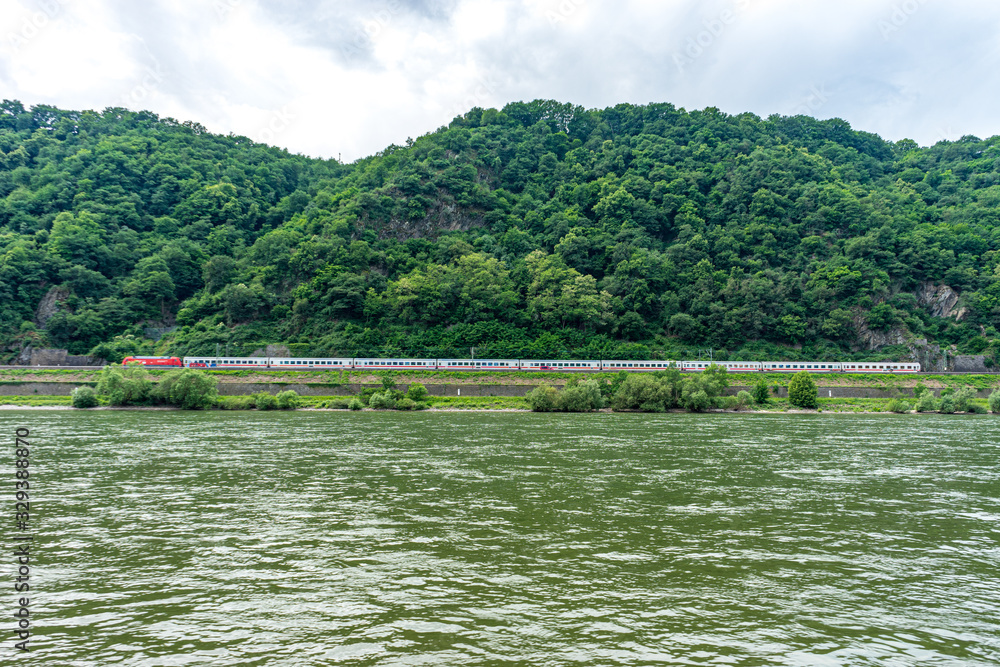 Germany, Rhine Romantic Cruise, a train traveling down tracks next to a body of water Germany, Rhine Romantic Cruise, a train traveling down tracks next to a body of water
