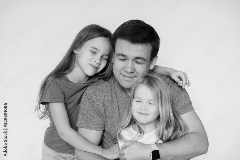 father and two daughters hug each. black-white.