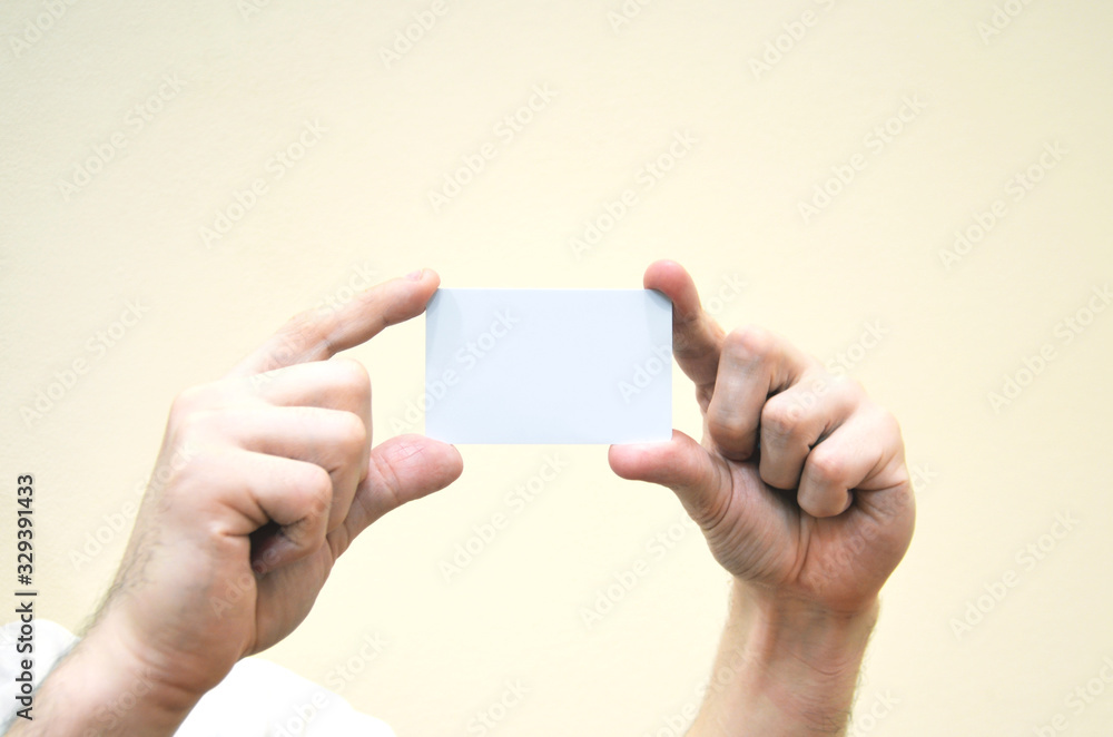 Business card in hands is clean and white. Credit, discount or bank card, customer card is not held in hand on a yellow background. Business card in hands is clean and white. Credit, discount or bank card, customer card is not held in hand on a yellow background.