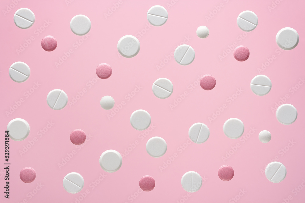 white and pink round medical pills on a color background