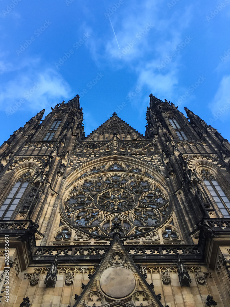 Prague castle St. Vitus Cathedral low angle view with traveling airplane trace in blue sky above