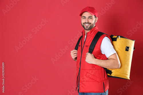 Courier with thermo bag on red background, space for text. Food delivery service photo