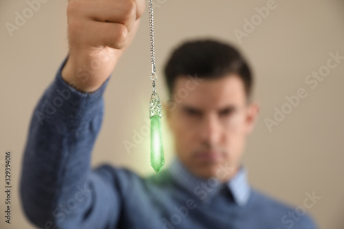 Vászonkép Psychotherapist with pendulum on beige background