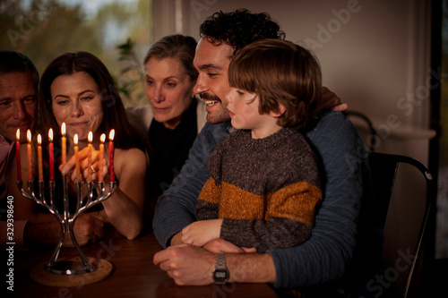 Konstfotografi Multigenerational family with lit candles on menorah during Hanukkah at home