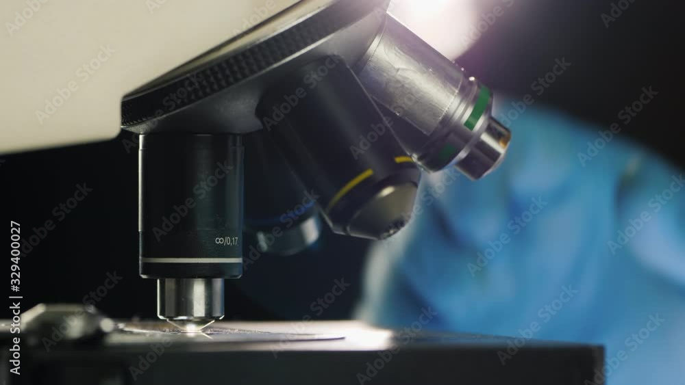 Side view of of a scientist working with a microscope in the lab Side view of of a scientist working with a microscope in the lab