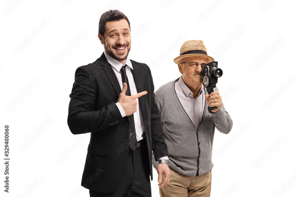 Young man in a suit pointing and laughing at an elderly man with a vintage camera Young man in a suit pointing and laughing at an elderly man with a vintage camera