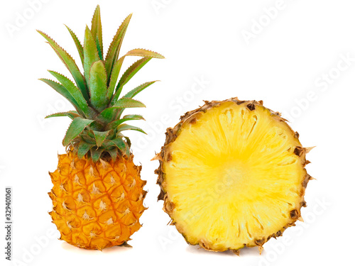 One whole baby pineapple with green leaves and a half of pineapple isolated on a white background
