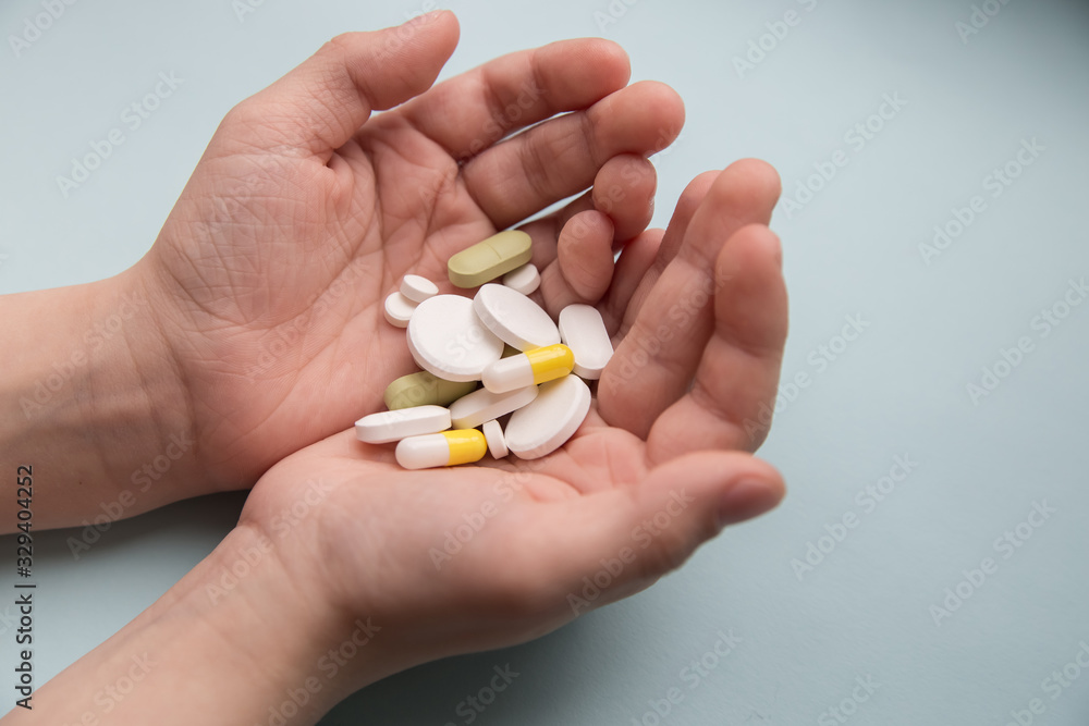 children hands holding pills on blue background children hands holding pills on blue background
