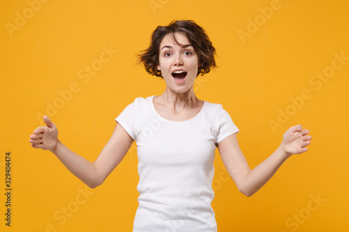 Foto Excited young brunette woman in white t-shirt posing isolated on yellow orange wall background