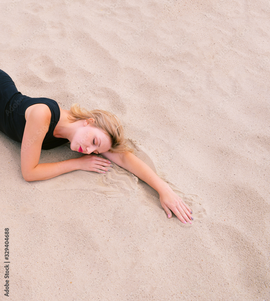 A young girl is sleeping on the sand. The view from the top A young girl is sleeping on the sand. The view from the top