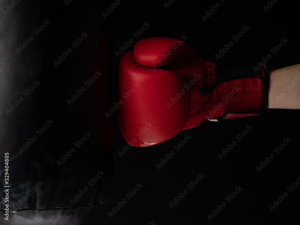 red boxing glove hitting the punching bag on black background