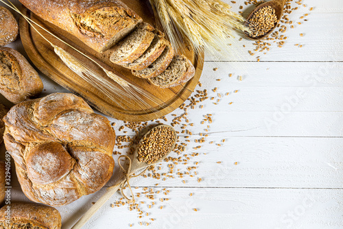 Obraz na płótnie Traditional wheat bread, rolls and ears of cereals on a white wooden background w salonie