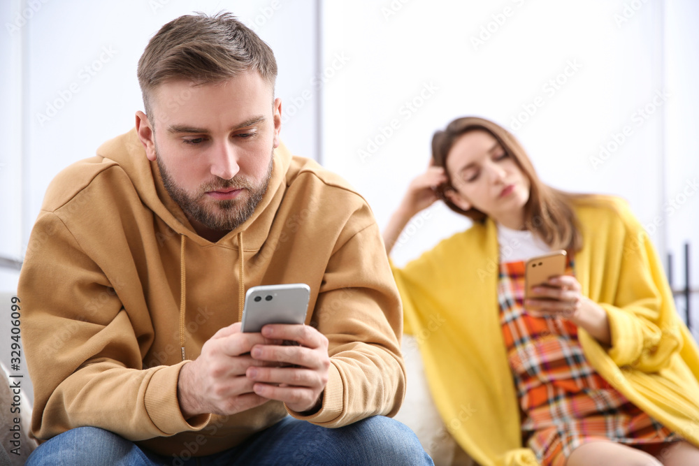 Couple addicted to smartphones ignoring each other at home. Relationship problems Couple addicted to smartphones ignoring each other at home. Relationship problems