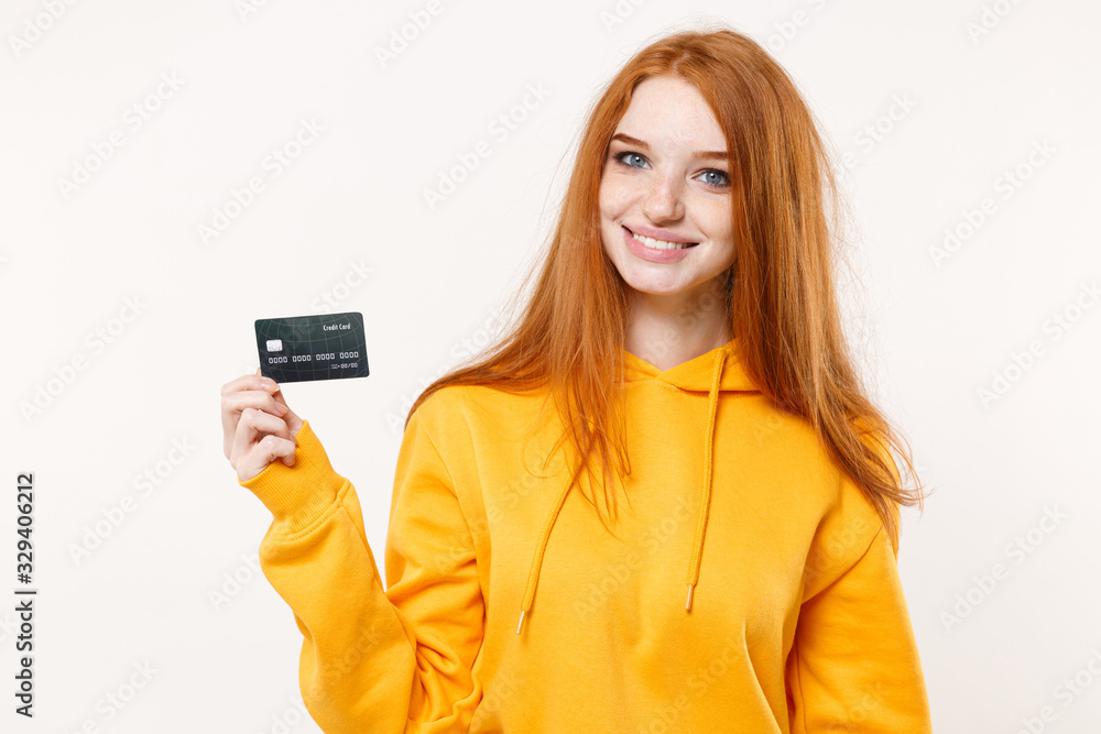 Smiling young redhead woman girl in casual yellow hoodie posing isolated on white wall background studio portrait. People sincere emotions lifestyle concept. Mock up copy space. Hold credit bank card. Smiling young redhead woman girl in casual yellow hoodie posing isolated on white wall background studio portrait. People sincere emotions lifestyle concept. Mock up copy space. Hold credit bank card.