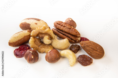 Mixed nuts and dried fruits in wooden bowl on white background, copy space