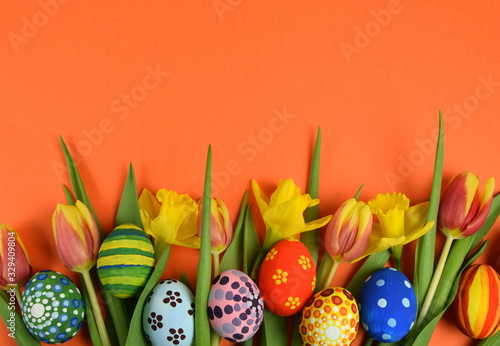 Happy Easter - painted eggs and daffodils on colored background photo