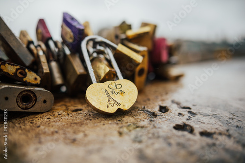 Eiffel Tower and Padlocks (love locks) on the bridge - Paris, France. Heart shaped vintage lock in Paris, France. Ritual of affixing padlocks, as symbol of love, to bridge. Rain day.