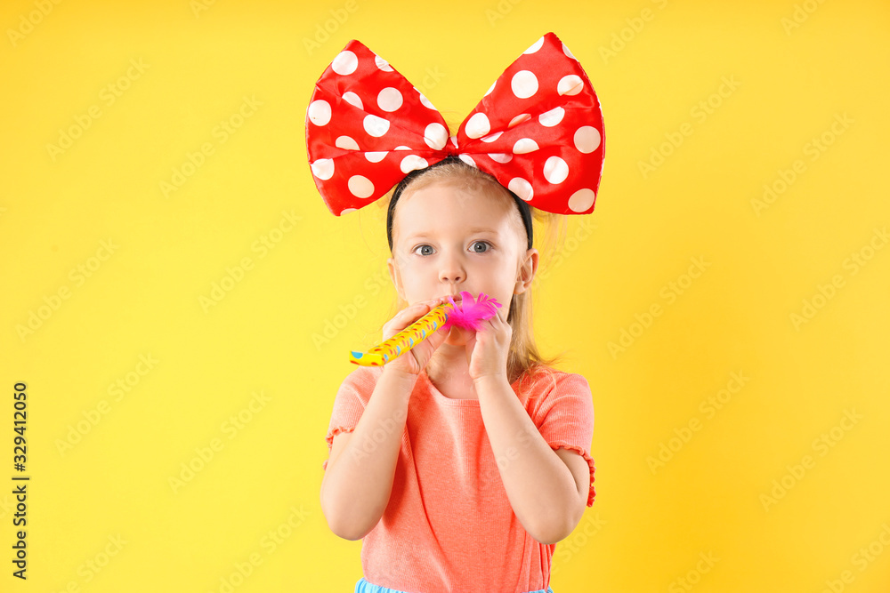 Little girl with large bow and party horn on yellow background. April fool's day Little girl with large bow and party horn on yellow background. April fool's day