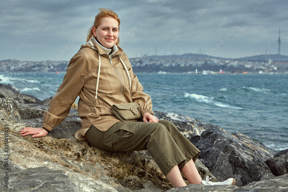 Young girl sits on a rock near the Golden Horn Bay