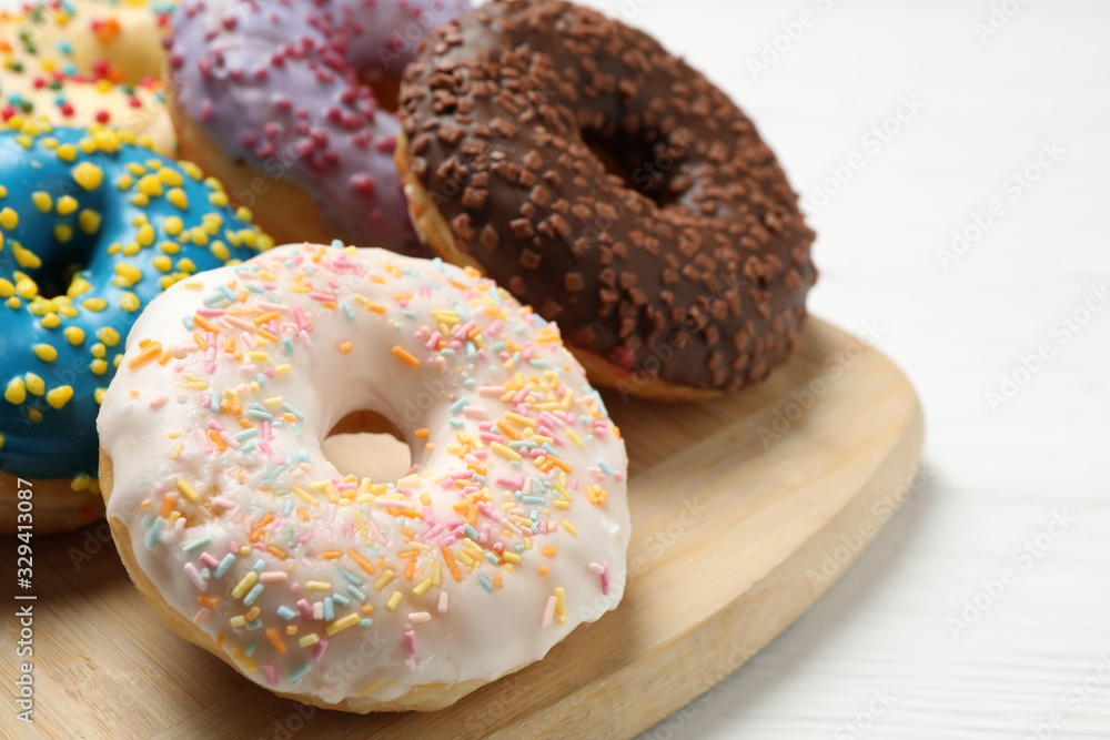 Yummy donuts with sprinkles on white wooden table, closeup
