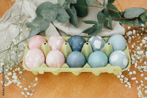 Easter eggs natural dye in carton tray on rustic table with flowers. Modern pastel pink and blue easter eggs painted with organic beets, red cabbage, carcade tea. Zero waste holiday photo