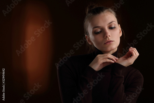 Beautiful girl in a maroon turtleneck on a brown background