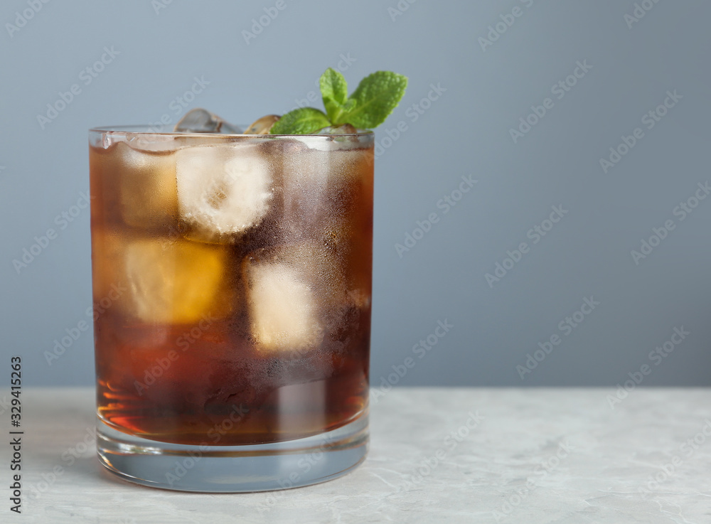 Tasty cocktail with ice cubes and mint on light marble table, closeup. Space for text Tasty cocktail with ice cubes and mint on light marble table, closeup. Space for text